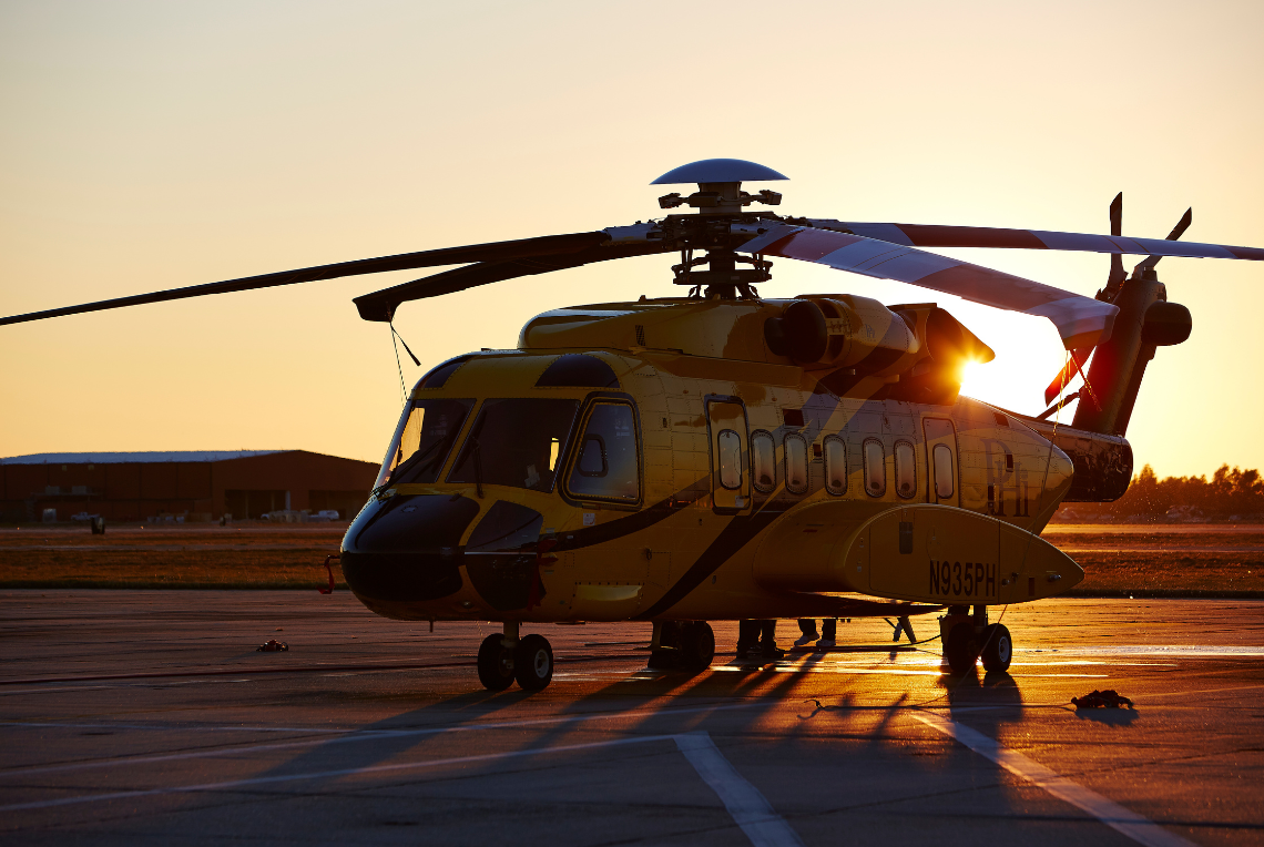 Sikorsky S-92 helicopter in PHI black and yellow paint scheme with sunset in background